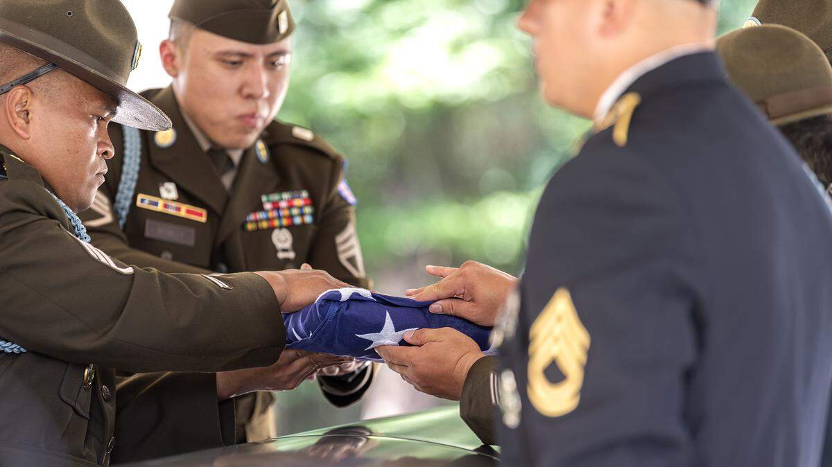 The honor guard carefully folds the United States flag over the casket of retired Staff Sgt. Robert J. Wolfenberger Jr. at his funeral service and burial Wednesday at Fort Mitchell National Cemetery in Fort Mitchell, Alabama.