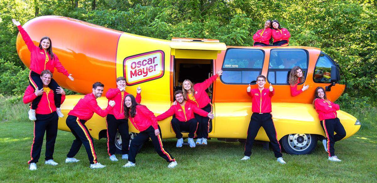Out of more than 7,000 applicants for the 2024-25 season, Oscar Mayer selected these 12 Wienermobile drivers, including Columbus native Sarah Oney (the person on the right in the “bun roof”). They are posing in Madison, Wisconsin, where the drivers trained for two weeks in June 2024.