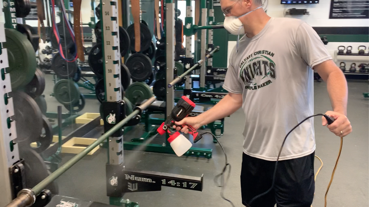 Calvary Christian head football coach Brian Osborne sprays down a weightlifting station on Thursday, June 11, 2020. The Knights recently started preseason workouts amid COVID-19.