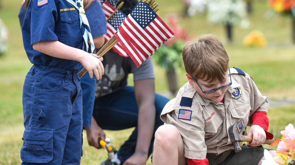 Ronan Hurst and Logan Hires place flags along the walkways leading to the Veterans Memorial at Parkhill Cemetery in Columbus, Georgia Sunday morning. The community service event was hosted by Cub Scout Pack 48 members in observance of Veterans Day 2020 and to honor all veterans and service members.