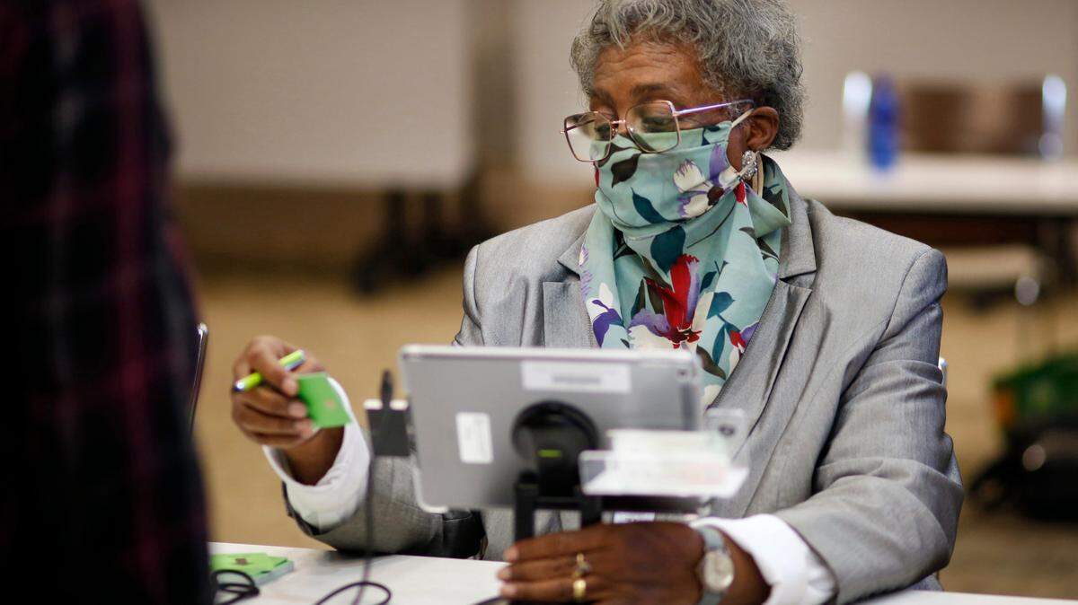 Helen B. Thompson, a poll worker at voting precinct 102 at the Columbus Public Library, 3000 Macon Road, in Columbus, Georgia, prepares to give a voter a voting card after checking them in Tuesday morning. 11/08/2022
