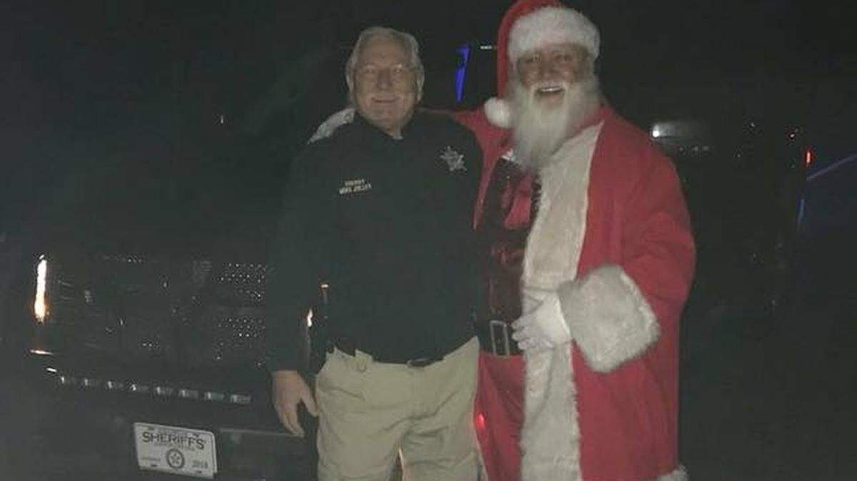 Harris County Sheriff Mike Jolley poses with Santa Claus after Jolley and his son, Cody, a reserve deputy, helped the unidentified man remove from Georgia Highway 85 a fallen pine tree that was blocking his way in the wee hours of Christmas morning Monday, December 25, 2017.