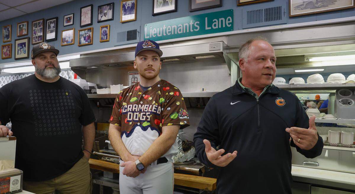 The Columbus Clingstones hosted a news conference April 9, 2026, at Dinglewood Pharmacy in Columbus, where Clingstones general manager Pete Laven, right, announced “Scrambled Dogs” will be one of the team’s alternate identities this season. The artwork for the jerseys and associated merchandise was done by Columbus artist and graphic designer Mike Jones, far left.
