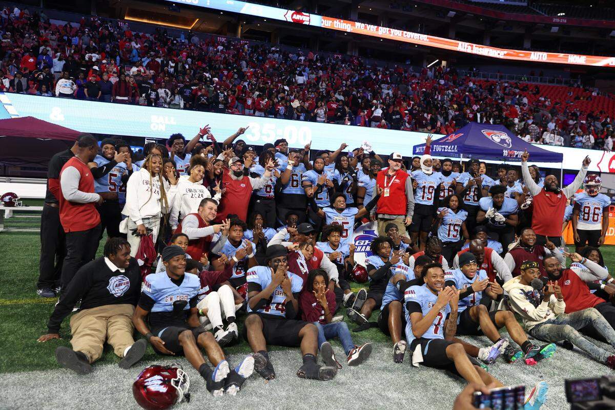 The Carver High School football team poses by pointing at their ring fingers after winning the Georgia High School Association Class AA state football championship with a 52-14 victory over the Burke County High School Bears on Dec. 17, 2024, at Mercedes-Benz Stadium in Atlanta.