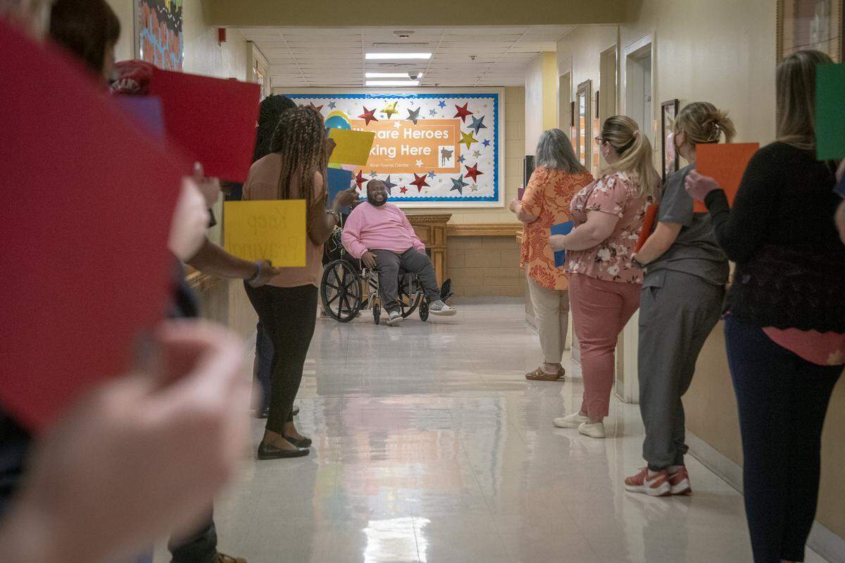 River Towne staff applaud and cheer on Eric Lofton as he leaves the nursing facility after nearly two months of recovery, on May 27, 2021, at River Towne Center nursing facility.