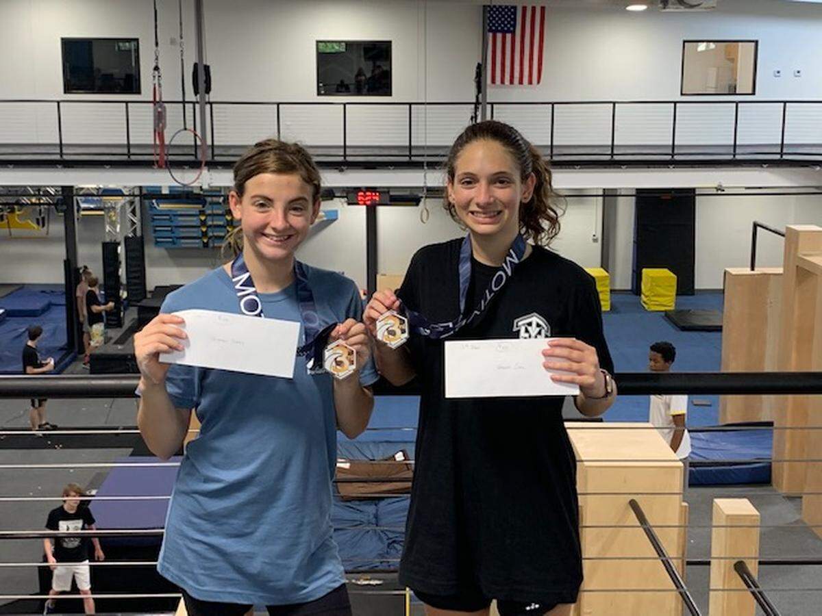 At the 2022 Southeast Parkour Championships in Greenville, S.C., Jordan Watson, left, and Jodi Behar of Level Up Parkour Academy in Columbus, Ga., pose with their third-place medals and $100 checks they won in the age 16-and-over women’s division: Jordan in the speed category and Jodi in the skills category.