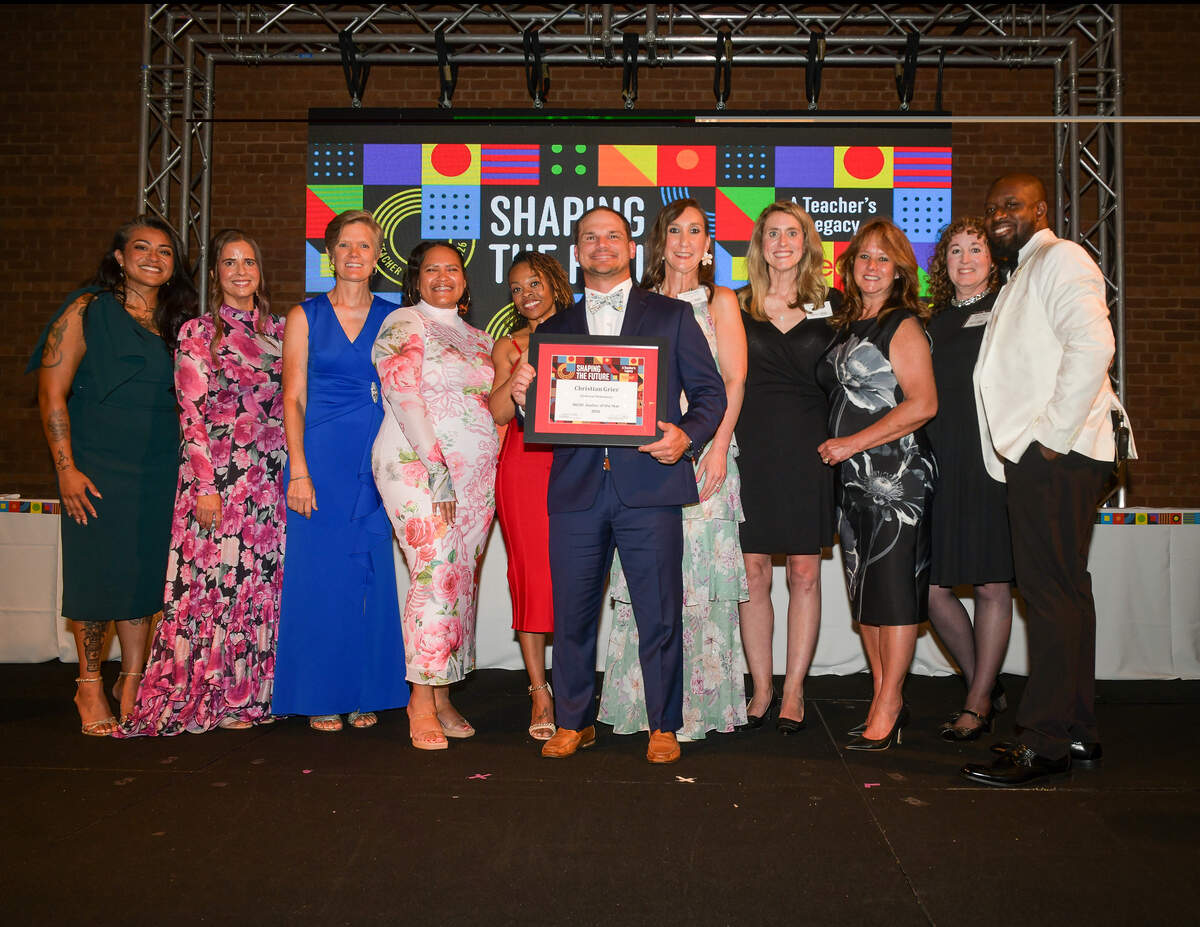 Clubview Elementary School physical education teacher Chris Grier holds his Muscogee County School District 2026 Teacher of the Year award and is joined on stage by past winners during the Muscogee Educational Excellence Foundation gala May 7 at the Columbus Convention & Trade Center.