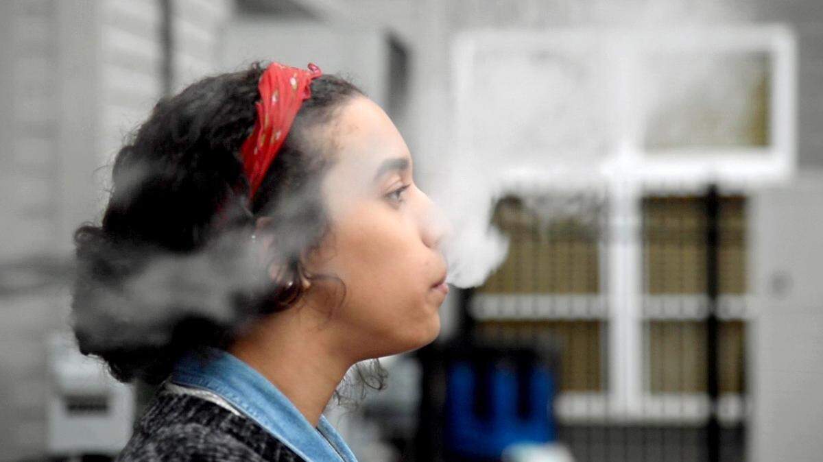 File photo: A college student in Georgia uses a Juul electronic cigarette in 2018 while on a quick break at work.
