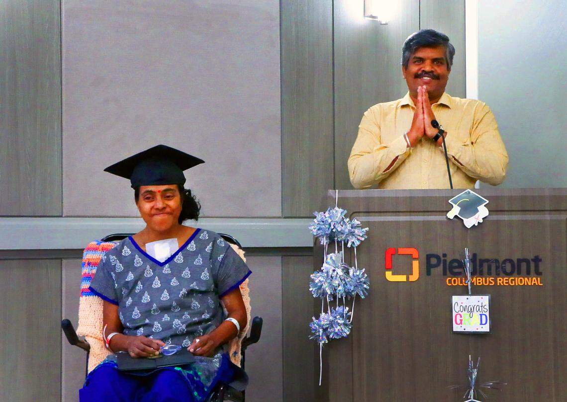 V. Balakumar stands next to his wife Mirna Balakumar during a graduation party Piedmont Columbus Regional hosted June 25, 2025, for Mirna, a patient at Piedmont who has been recovering since she was struck by a car in April, three days after earning a master’s degree.