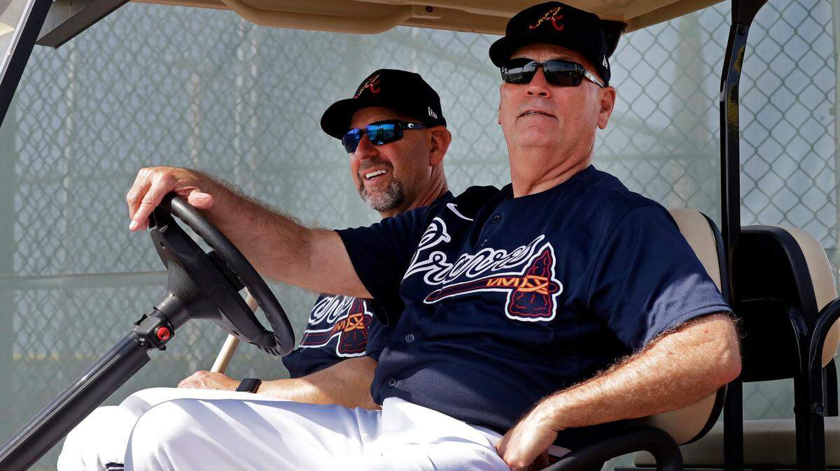 Atlanta Braves manager Brian Snitker, right, and bench coach Walt Weiss watch from a golf cart as the pitchers and catchers get loose during spring training baseball camp Thursday, Feb. 13, 2020, in North Port, Fla. (AP Photo/John Bazemore)
