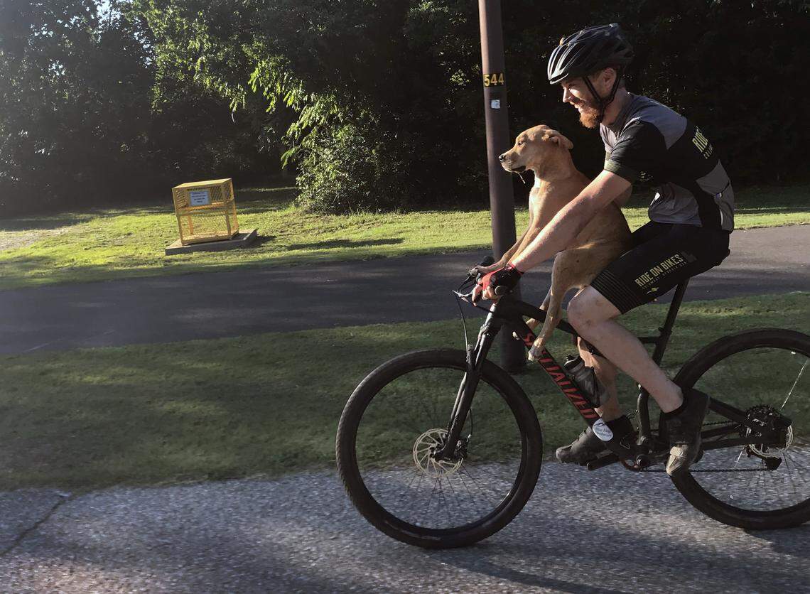 Columbo holds onto Jarrett Little as Little gives him a ride from the roundabout near South Lumpkin Road and the entrance to the Columbus Water Works sewage treatment facility to downtown Columbus.