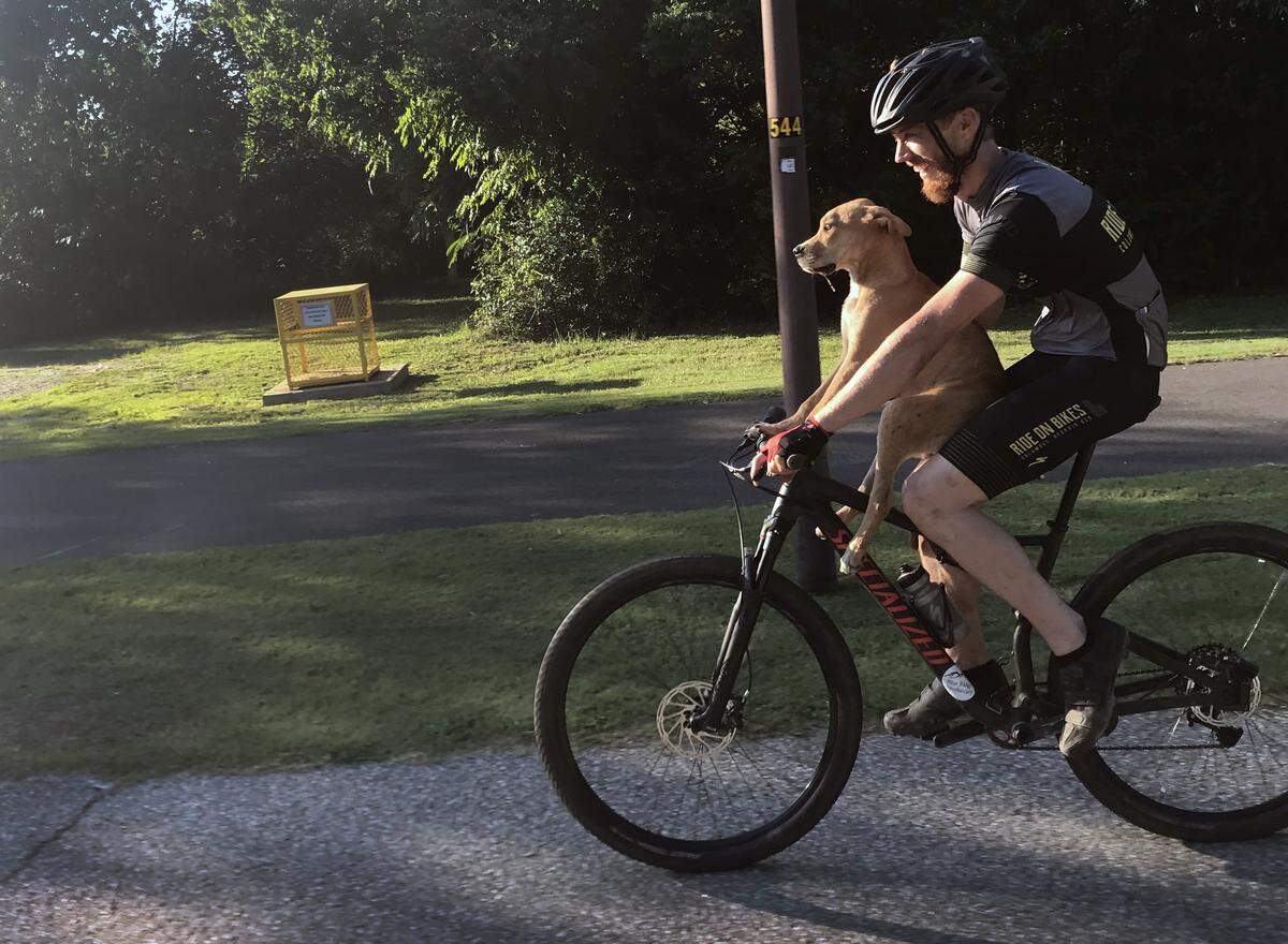 Columbo holds onto Jarrett Little as Little gives him a ride from the roundabout near South Lumpkin Road and the entrance to the Columbus Water Works sewage treatment facility to downtown Columbus.