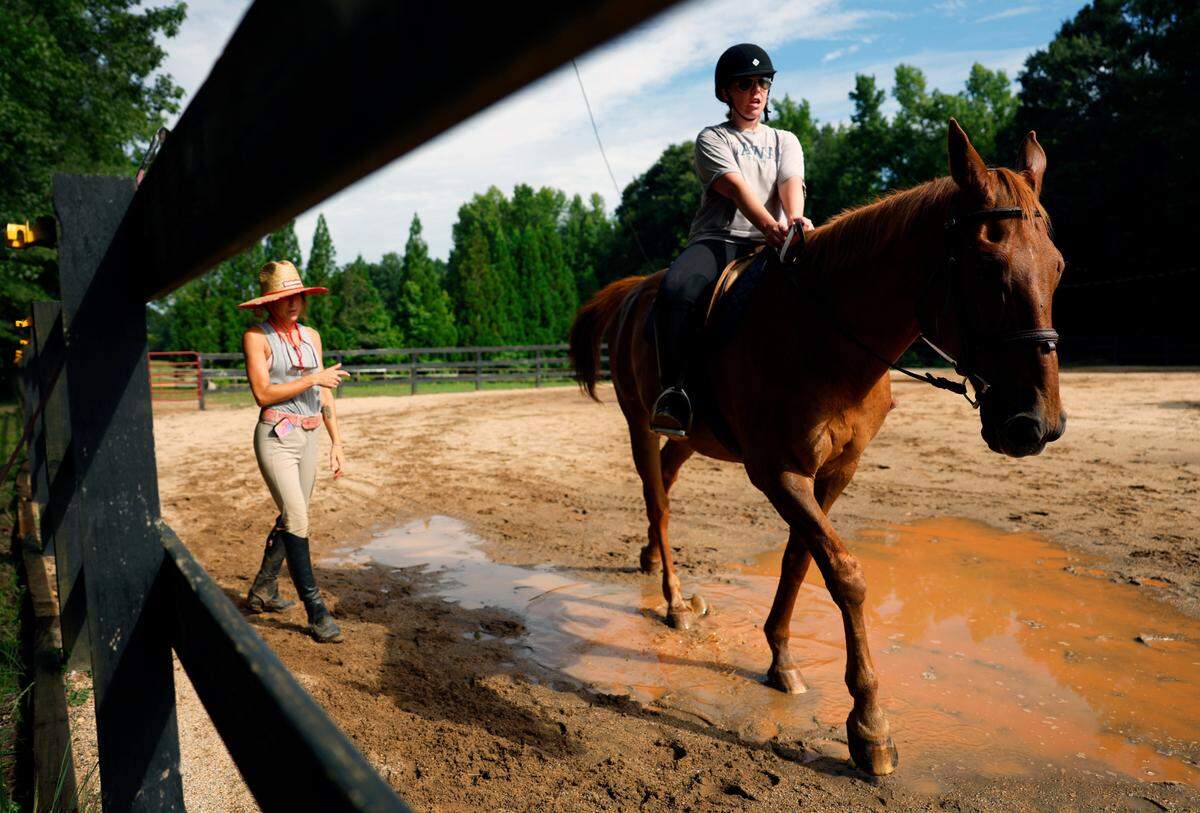 Olivia Oney, standing left, a riding instructor, horse trainer, and the owner of Double O Sporthorses, in Hamilton, Georgia, works with a student..