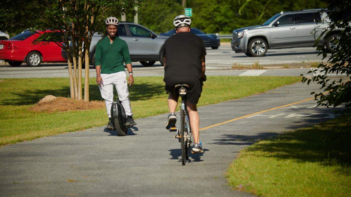 Cyclist and electric-unicyclist using the Dragonfly Trail path to get around Columbus