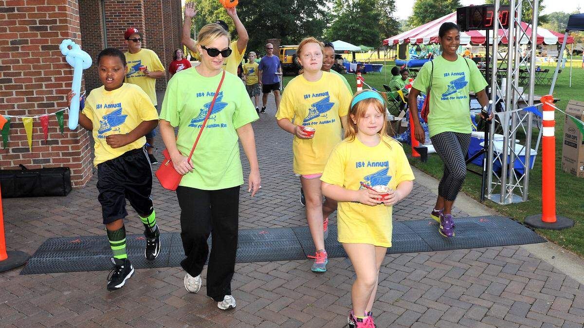 Runners cross the finish line of the Miles for Autism 5k and Fun Run on Saturday morning at Woodruff Park.