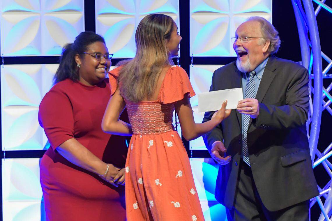 Columbus High School senior Megan Taylor, center, receives a $1,000 check from Piedmont Columbus Regional community relations director Joel Ames for winning the 2025 Page One Award in the journalism category during Tuesday night’s ceremony at the RiverCenter for the Performing Arts in downtown Columbus. On stage with them is Ledger-Enquirer reporter Brittany McGee, one of the judges for the journalism category