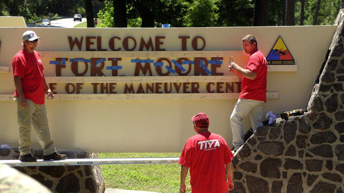 Workers change the name on a welcome sign on Ft. Benning road to “Fort Moore” on Tuesday afternoon. 05/02/2023