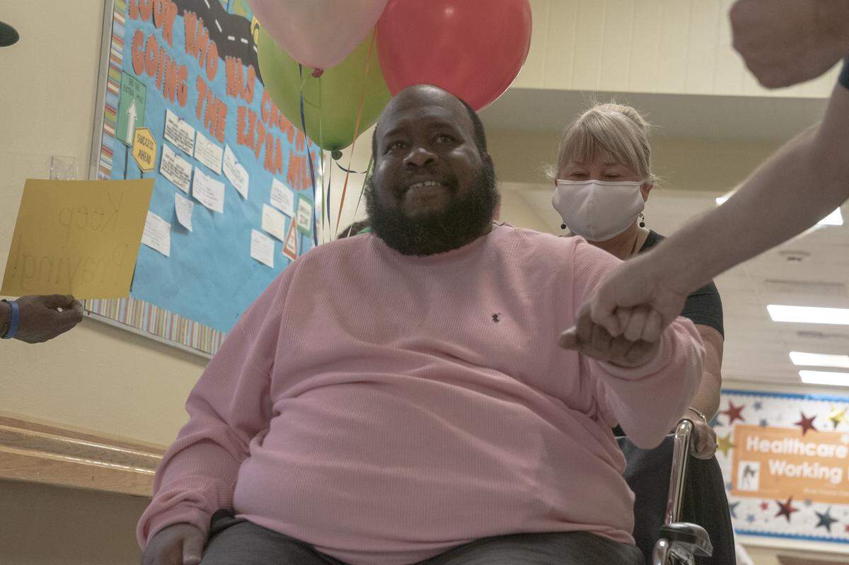 Eric Lofton fist pounds a respiratory therapist on his way out of River Towne Center nursing facility, on May 27, 2021, in Columbus, Ga.