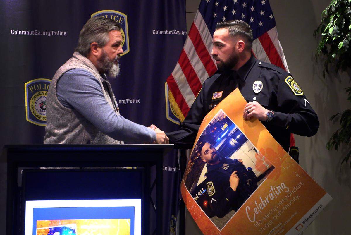 Mike Brown, the director of public safety for Piedmont Columbus Regional, left, recognizes Columbus Police Officer Tim Millheiser as a First Friday Hero during a ceremony on Jan. 16, 2025 at the Public Safety Building in Columbus, Georgia. Millheiser rescued three people, including one he carried out, from an apartment fire in Columbus, Georgia.