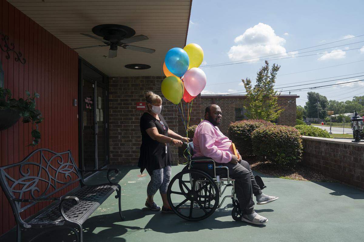 River Towne’s activity director Julia Taylor wheels Eric Lofton to the curb as his girlfriend gets the car on May 27, 2021, at River Towne Center nursing facility in Columbus, Ga.