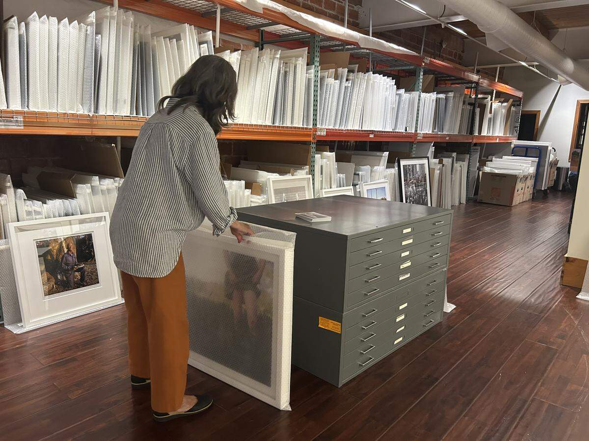 The Do Good Fund photography gallery’s collection manager, Hallie Fivecoat, unwraps a photo July 29, 2025, in the gallery at 111 W. 12th St. in Columbus.