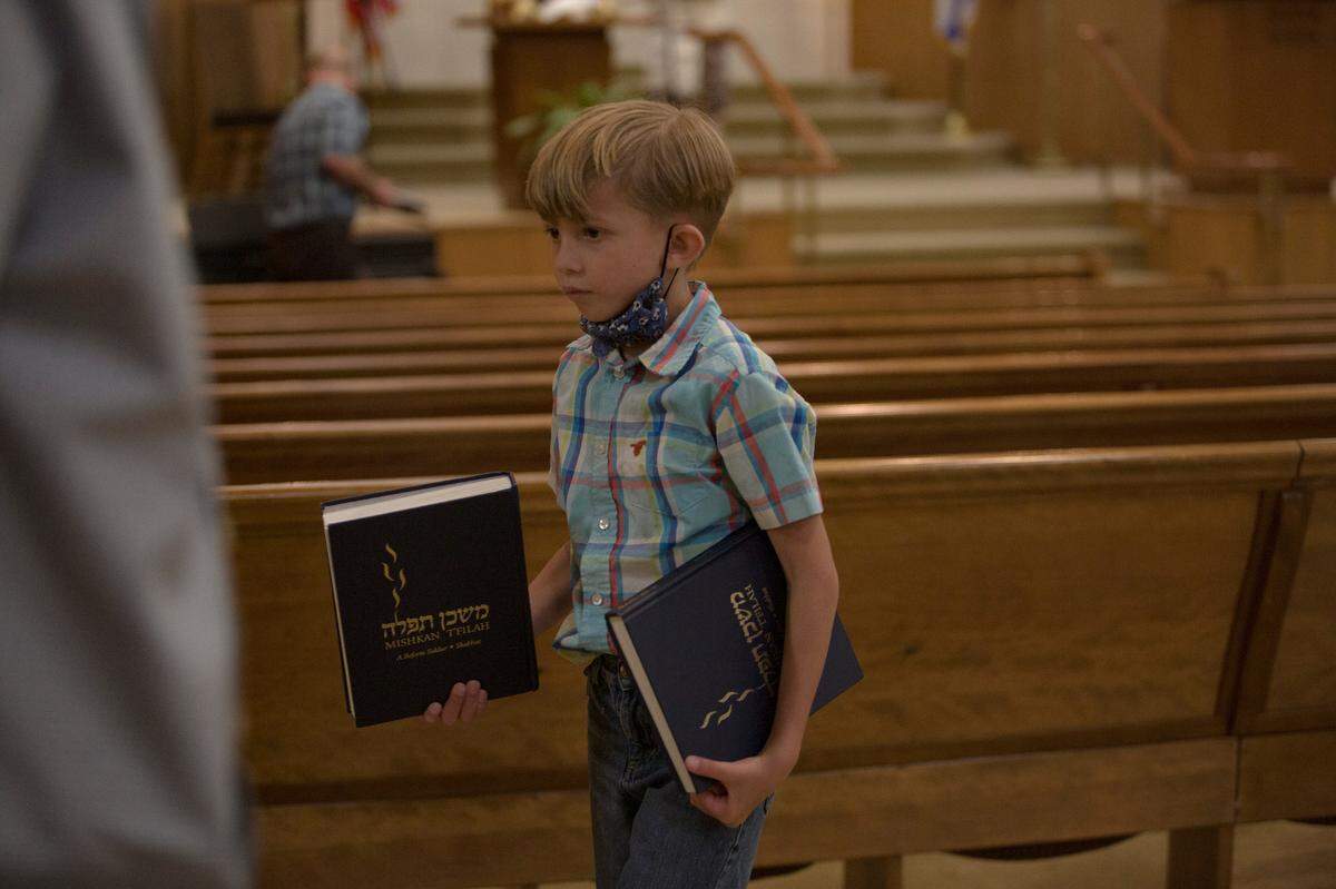 A young congregant passes out prayer books before Shabbat service at Temple Israel on June 18, 2021, in Columbus, Ga.