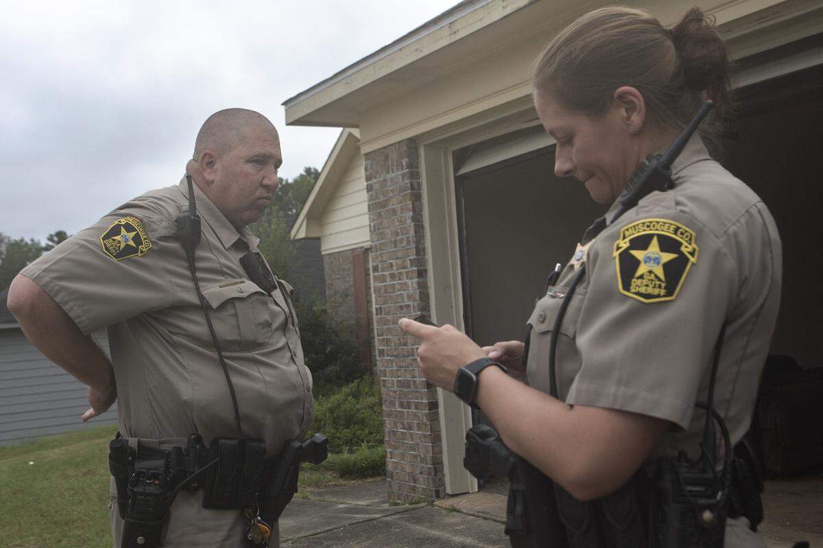 Deputies David Podger and Hilary Rager wait as movers empty a home on July 20, 2021, in Columbus, Ga. Deputies on-scene are responsible for enforcement and peacekeeping during the eviction process.