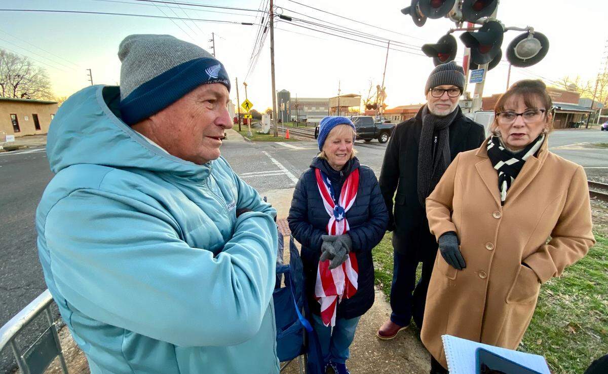 Richard Smith, far left, of Largo, Florida, talks about why he and his wife drove up from Florida to Plains, GA early on the morning of Jan. 4, 2025, to witness former President Jimmy Carter’s motorcade.