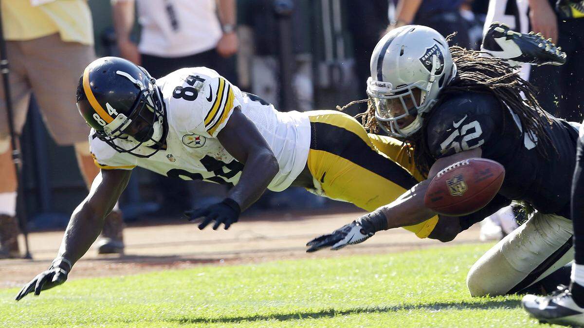 Pittsburgh Steelers wide receiver Antonio Brown, left, fumbles the ball near the goal line as Oakland Raiders linebacker Philip Wheeler, right, looks on during the third quarter of an NFL football game in Oakland, Calif., Sunday, Sept. 23, 2012. An unnecessary roughness penalty against the Raiders was called on the play giving the Steelers a touchdown. (AP Photo/Marcio Jose Sanchez)