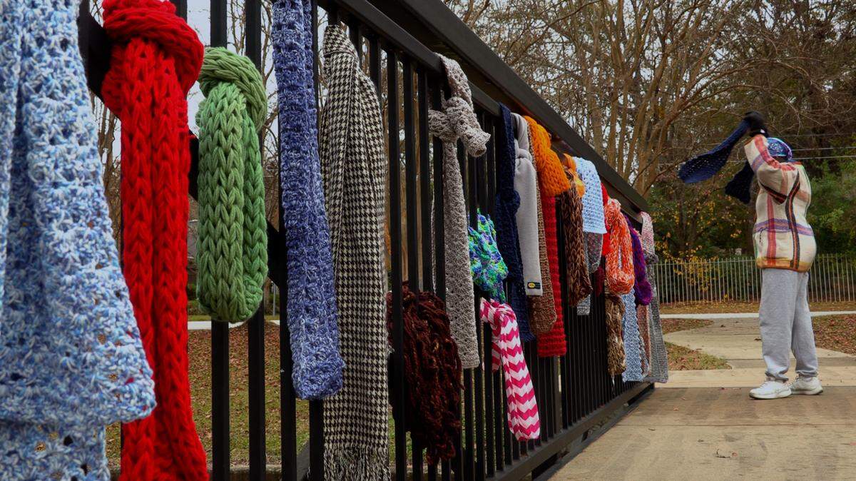 A woman wraps a scarf around her neck Monday morning at Lakebottom Park in Columbus. Preschoolers from the St. Paul Preschool at St. Paul United Methodist Church, teachers, and staff filled this bridge over Wearcoba Creek at Lakebottom Park with brightly-colored scarves during their Third Annual Hanging out at the Bridge event. Nan Konze, the preschool director, said the scarves are meant for anyone to take as needed at no cost. She said the scarves are collected by students throughout the school year, and some are knitted by volunteers. There are about 70 children ages eight weeks through four years in the school, with the three and four-year-olds participating in Monday’s event. Go to www.ledger-enquirer.com for video from the event.