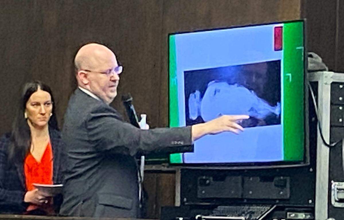 Prosecutor Cara Convery watches as medical examiner Steven Atkinson points to an X-ray.