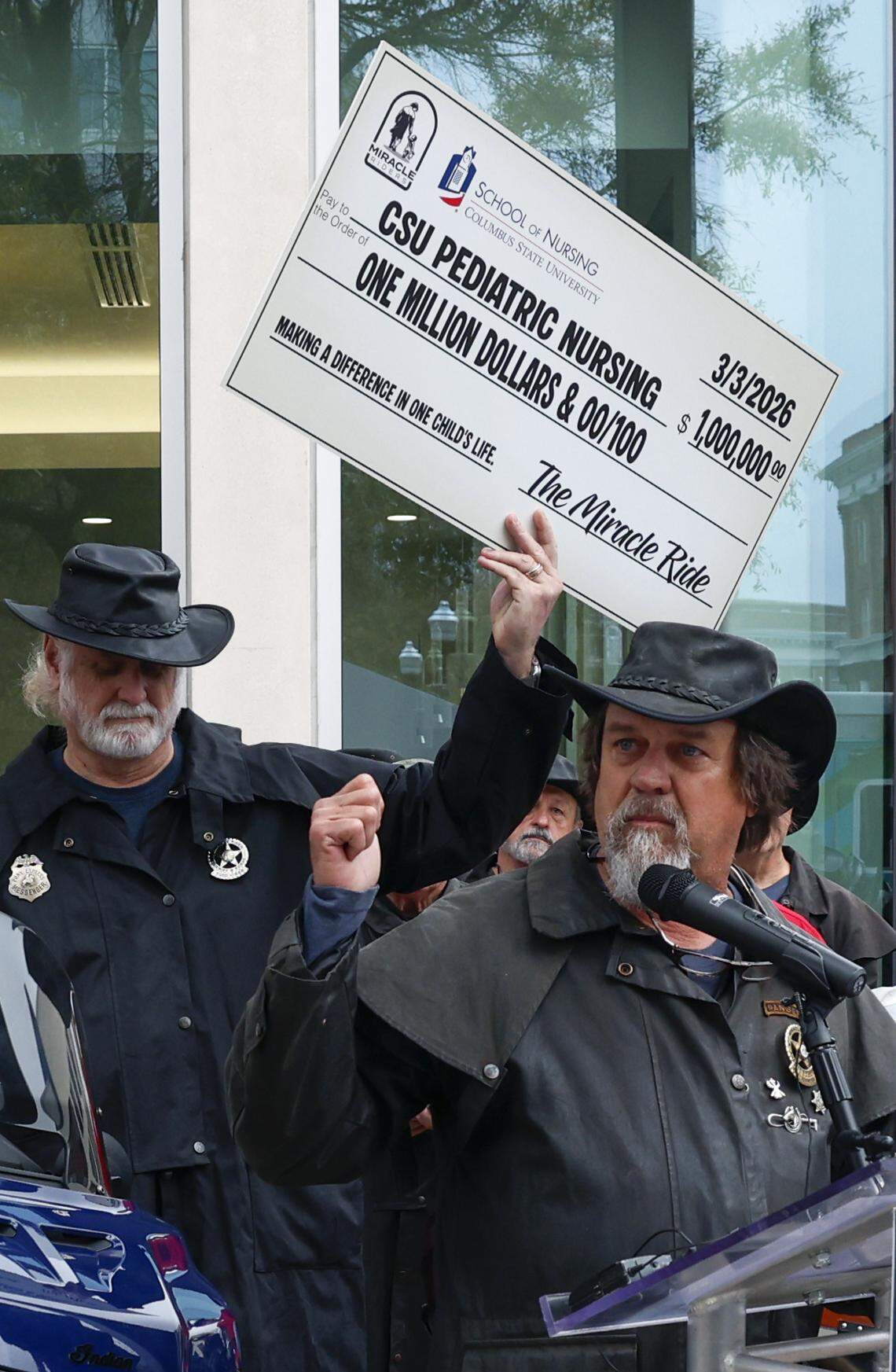 The Miracle Riders have hit their $1 million fundraising goal for Columbus State University. Scott Ressmeyer, co-owner of Country’s Barbecue and founder of the Miracle Ride, front, makes the announcement March 3, 2026, in front of CSU’s Frank D. Brown Hall in downtown Columbus.