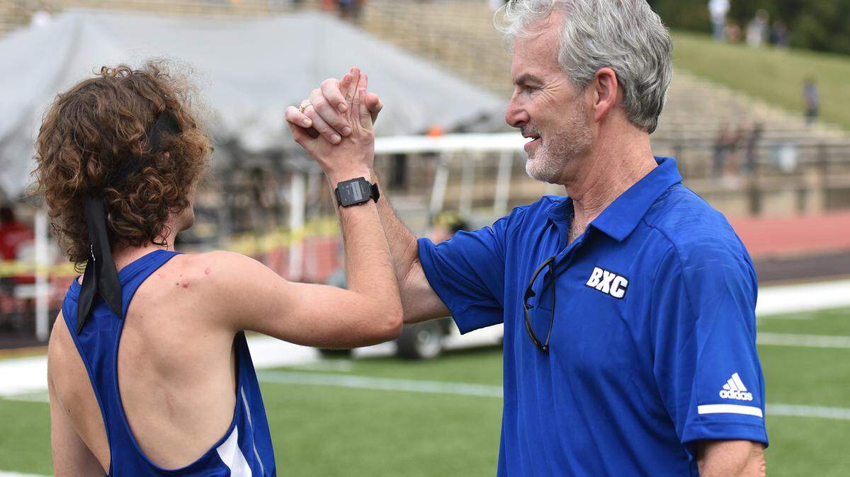 Brookstone’s Ryan Drew shares a high five with coach Mark Erb after the Cougars won of city’s boys cross country championship and Erb won the Coach of the Year award Tuesday, October 16, 2018, at Shaw High School.