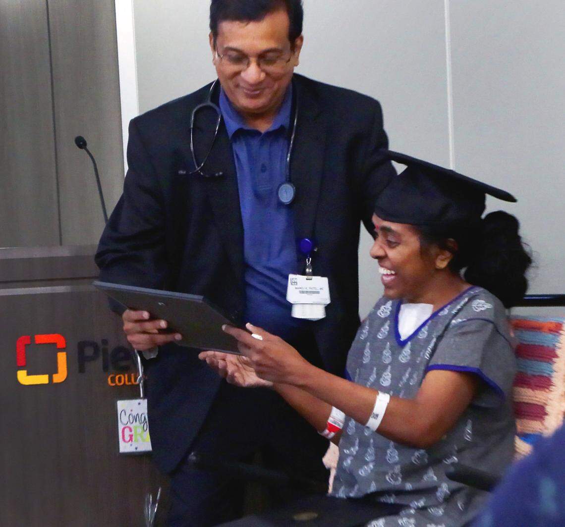 Dr. Manoj Patel, MD, presents Mirna Balakumar with a diploma at a graduation party hosted by Piedmont Columbus Regional on June 25, 2025, for Balakumar, a patient at Piedmont who has been recovering since she was struck by a car in April, three days after earning a master’s degree.