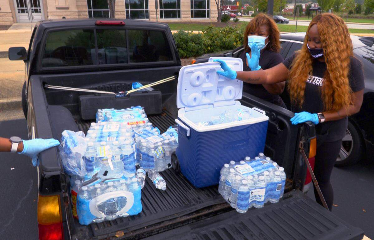 Rosalene Horace and Teri Hall prepare to give out free bottled water to people waiting in line Monday morning to vote at the Citizens Service Center in Columbus, Georgia. Voters turned out in force Monday for the first day of in-person advance voting at the Citizens Service Center in Columbus. At one point before noon more than 500 people were lined up outside the building.