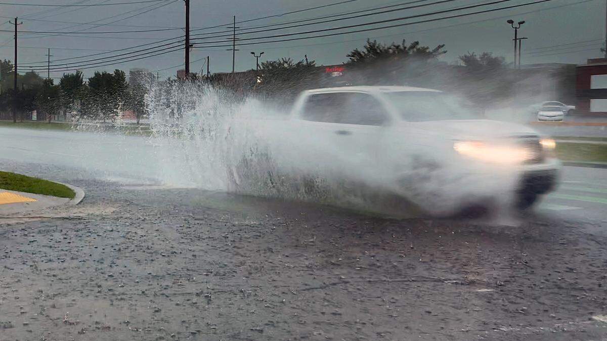 A motorist drives through standing water near the intersection of 14th Street and 5th Avenue in Columbus, Georgia during a heavy rainstorm. 06/14/2023