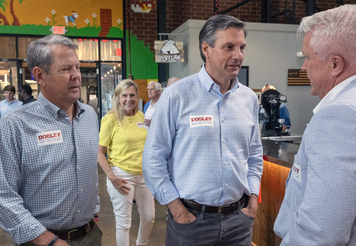 Former college football coach Derek Dooley, center, a Republican candidate for U.S. Senate, and Gov. Brian Kemp, left, talk with state Sen. Randy Robertson (R-Cataula) during Dooley’s campaign stop June 12, 2026, in Columbus. In the background is Georigia first lady Marty Kemp.