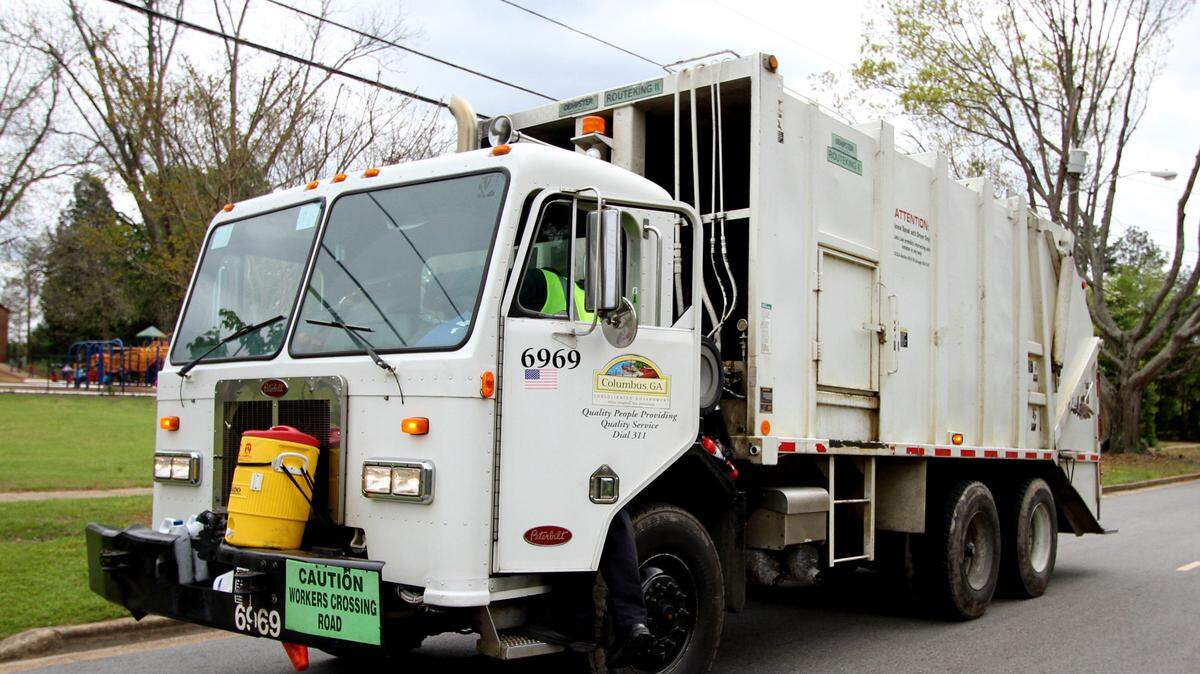 A garbage trucks drives down Fifth Avenue in Columbus, Georgia.