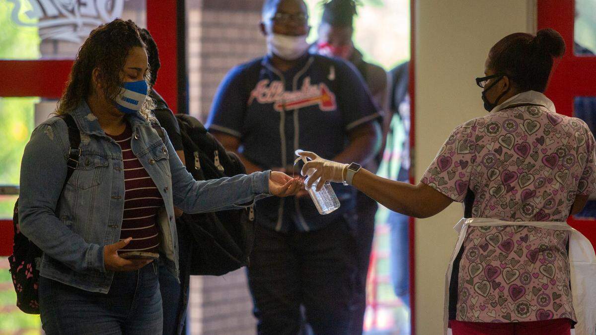 Cafeteria staff greet students with a grab-and-go breakfast and hand sanitizer on the first day of classes at Central High School on Tuesday, August 18, 2020 in Phenix City, Ala.