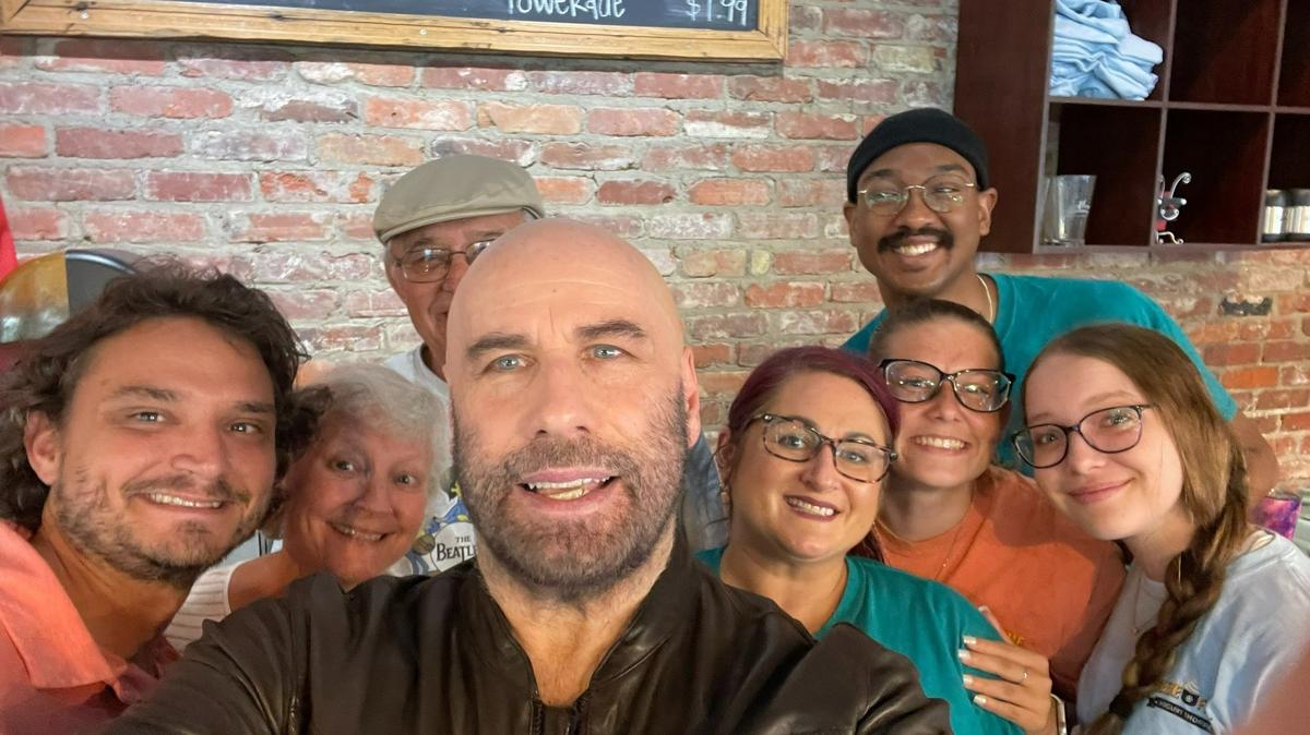 Hollywood actor John Travolta poses for a photo June 13, 2022, at Freeze Frame Yogurt Shoppe in downtown Columbus. Travolta is starring in the movie “Cash Out” being filmed in Columbus. Surrounding him in the photo are, from left, Freeze Frame co-owner, along with family and staff members Garrett Tyler, Ginger Tyler, George Tyler, Stevie Hodge, Kiarra Hicks, Bryant Alcorn and Mallory Parrish.