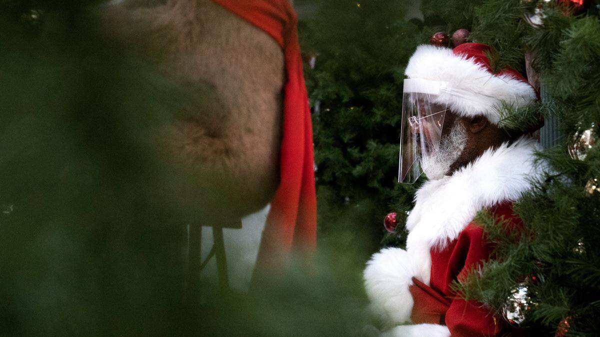 Wearing a face shield and keeping his distance, Santa waits to greet kids at the Peachtree Mall in Columbus, Georgia, on Friday, Dec. 18, 2020.