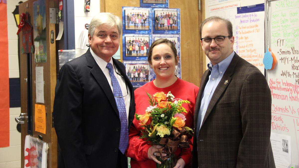Harris County School District superintendent Roger Couch, left, and board chairman Shane Lipp congratulate Mulberry Creek Elementary School fourth-grade English language arts and social studies teacher Mallory Naugher for being named the district’s Teacher of the Year.