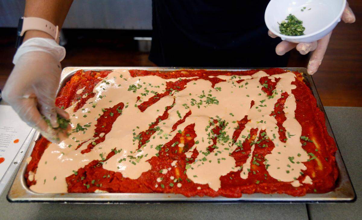 Terriann White, the kitchen supervisor at Country Life in Columbus, adds chopped green onions to a pan of their vegan lasagna. 05/05/2025
