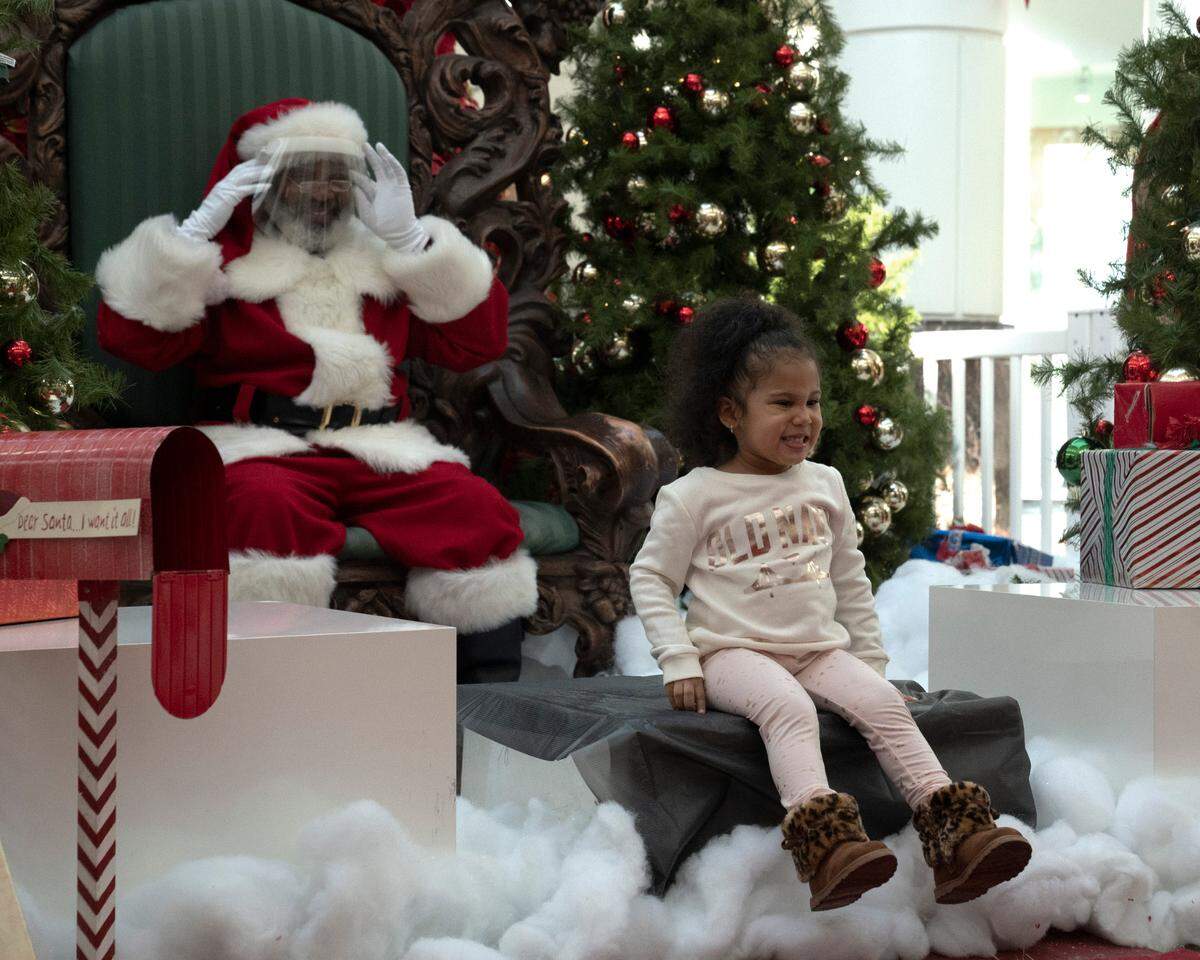 Eva Silberman, 3, flashes a big smile while getting her picture taken with Santa Claus at the Peachtree Mall in Columbus, Georgia, on Friday, Dec. 18, 2020.