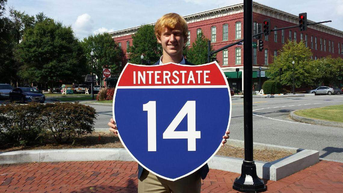 Columbus native Frank Lumpkin IV holds an Interstate 14 sign in 2018