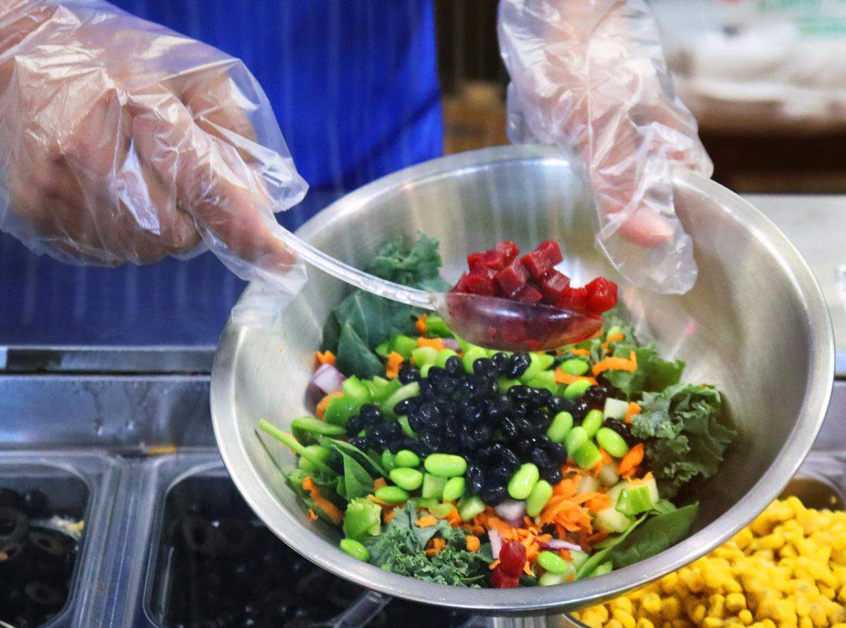 Hati Budiyono, co-owner of Build Yo Salad builds a vegan salad with avocado for under $11.
