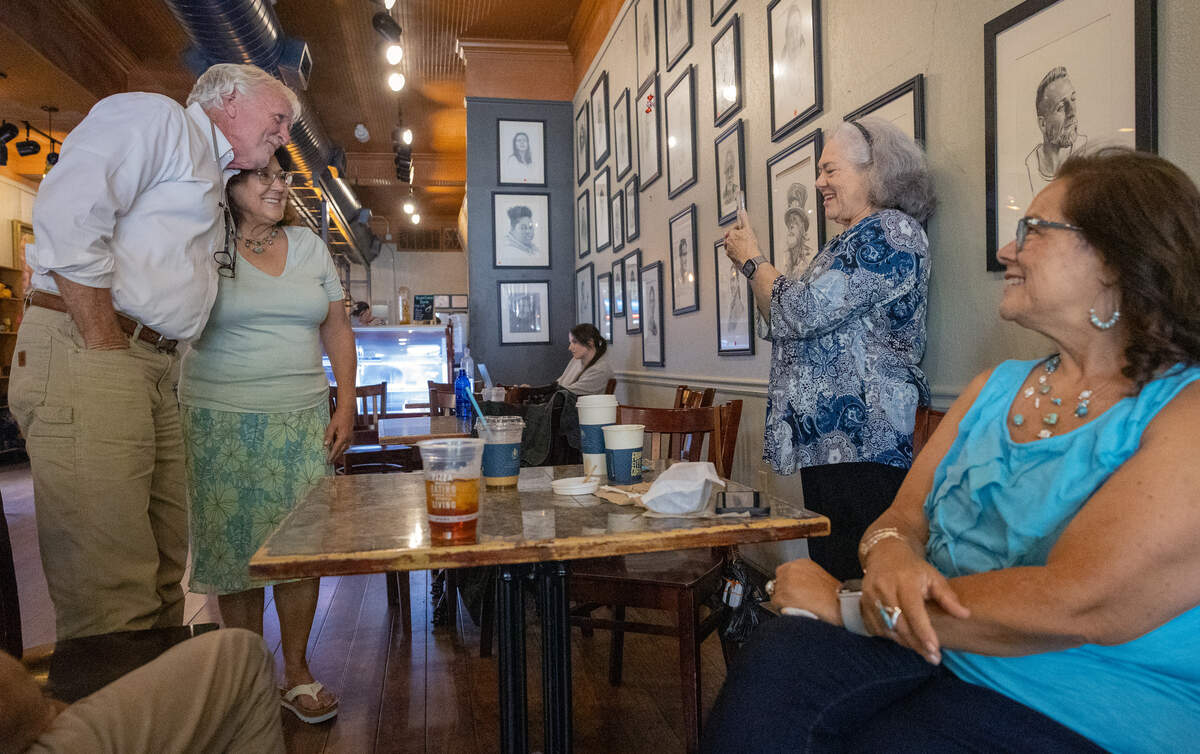 Midland resident Cheryl Buttler poses for a photograph June 25, 2026, with “Theo of Golden” author Allen Levi at Fountain City Coffee in Columbus. Buttler was at the coffee shop with her sisters Linda Pease, seated right, and Charmaine Bagg, taking the photo.