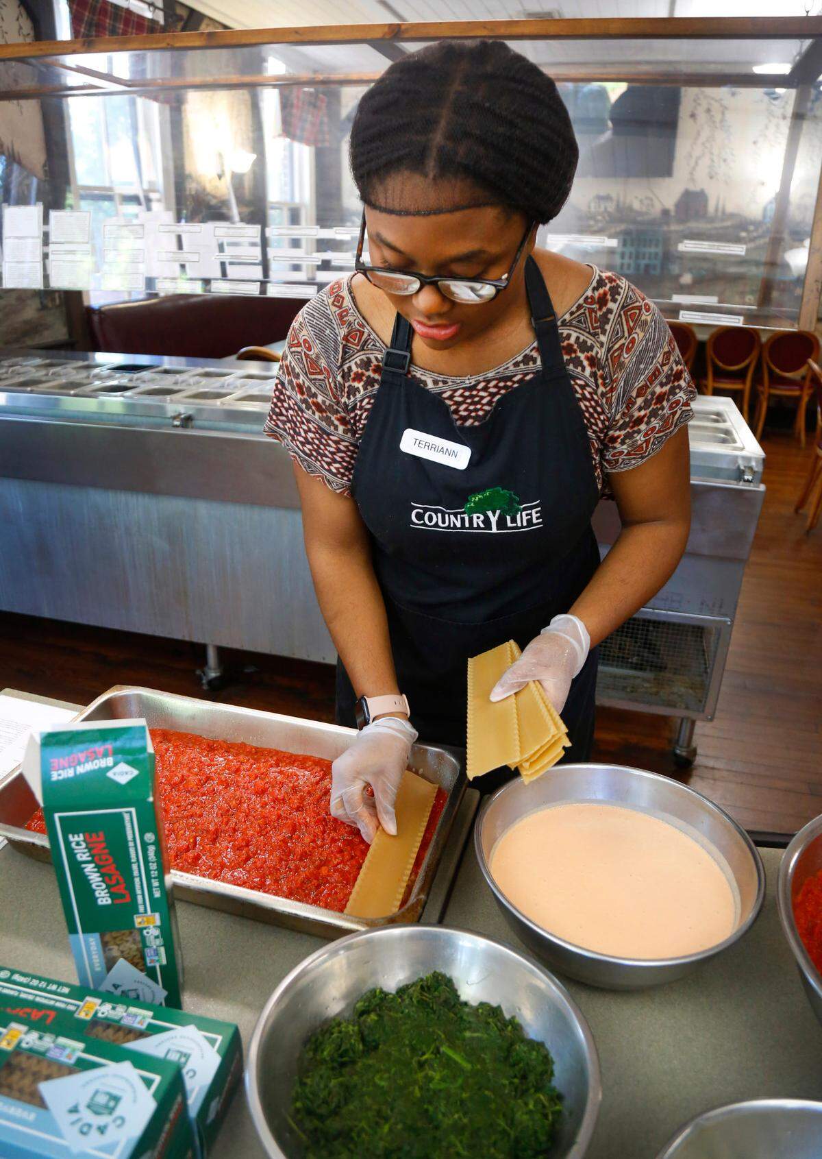 Terriann White, the kitchen supervisor at Country Life in Columbus, prepares a pan of their well-loved vegan lasagna recipe that uses brown rice lasagna. 05/05/2025