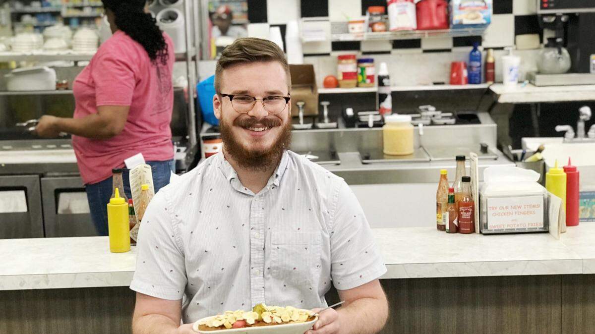Reporter Nick Wooten eats his first scrambled dog at Dinglewood Pharmacy on March 12.