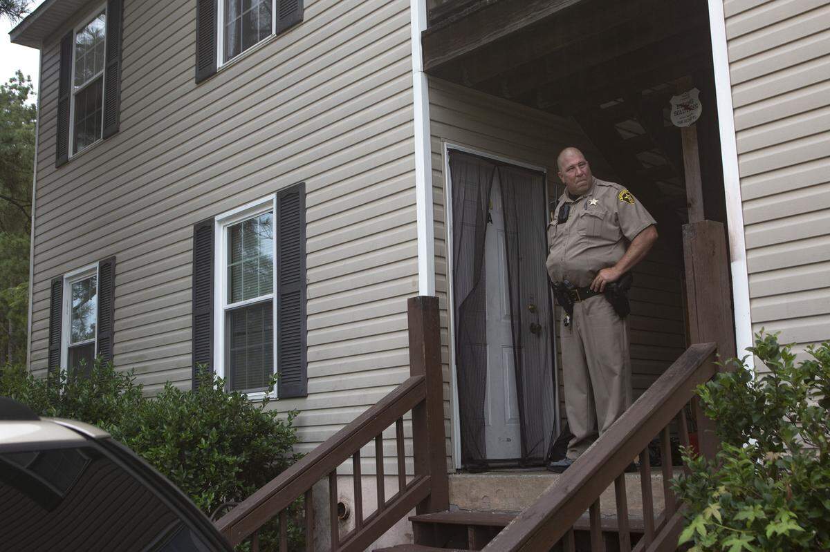 After knocking, Deputy David Podger waits for tenants to answer the door to begin an eviction on July 20, 2021, in Columbus, Ga.